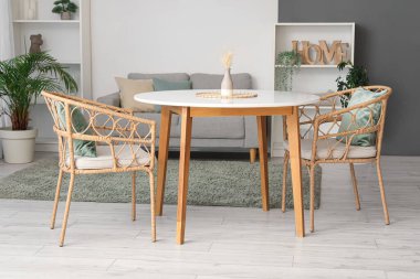 Masası, koltukları, rahat koltuğu, çiçekleri ve raf ünitesi olan modern oturma odasının güzel iç mekanı.