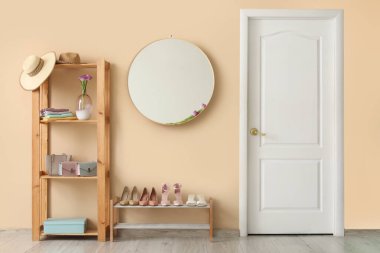 Ahşap depolama rafı, ayna, ayakkabı koleksiyonu ve bahar çiçekleri olan şık bir koridor.