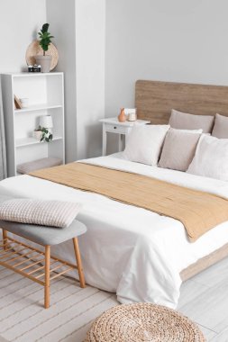 Yataklı, raflı, yastıklı ve komodinli bir yatak odası.