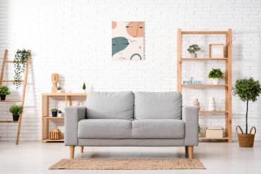 Beyaz tuğla duvarın yanında kanepesi olan modern oturma odası.