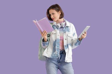 Leylak arkaplan üzerine kitap ve tablet bilgisayarı olan güzel bir öğrenci.