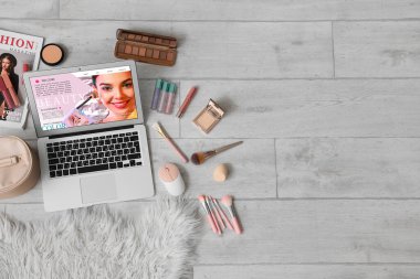 Açık güzellik blogu ve makyaj ürünleri olan dizüstü bilgisayar açık ahşap zemin, üst görünüm