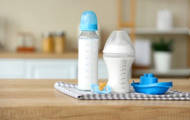 Bebek sütü formülü, emzik ve oyuncak tekne, ahşap mutfak tezgahında.