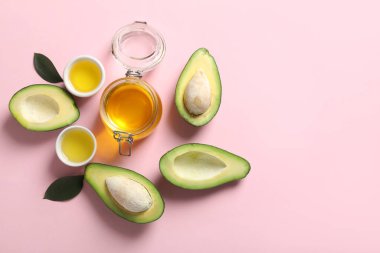Pembe arka planda olgun avokado, kavanoz ve kase yağlı kompozisyon