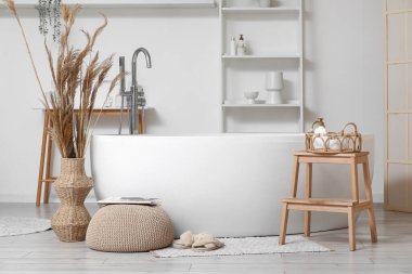 Şık banyoda, küvetin yanında, halının üzerinde yumuşak terlikler.