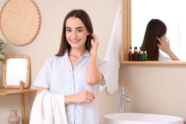 Banyoda aynanın yanında havlusu olan genç bir kadının sabahı.