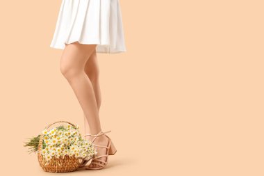 Bej arka planda hasır sepet papatya çiçekleri olan genç bir kadın.