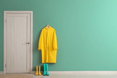 Kapısı, yağmurluğu ve çizmeleri olan şık bir koridor.