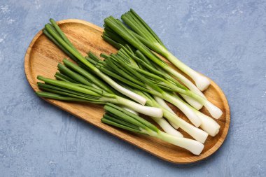 Mavi zemin üzerinde taze yeşil soğan olan tahta