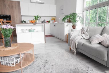 Açık mutfak planı, kahve masası ve gri kanepe.