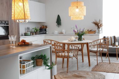 Modern mutfak, yemek masası, ada ve parlayan lambalar.