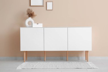 Dekorlu modern çekmeceler ve odadaki bej duvarın yanında boş resimler.