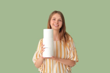 Young woman with toilet paper rolls on green background