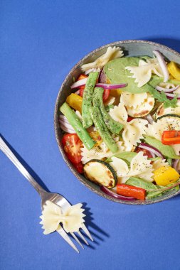 Kırmızı soğanlı ve biberli bir tabak lezzetli makarna salatası.