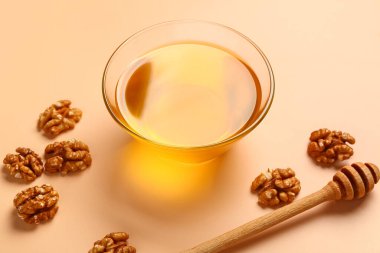 Bej arka planda ceviz ve dipli bir kase tatlı bal.