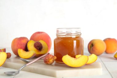Tatlı şeftali reçelli kavanoz ve masada taze meyve.