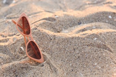 Kum üzerinde şık bej güneş gözlükleri