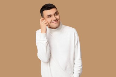 Kahverengi arka planda yakışıklı, utangaç genç bir adam.