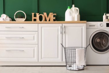 Çamaşır sepeti, çamaşır makinesi ve tezgahlı odanın içi.