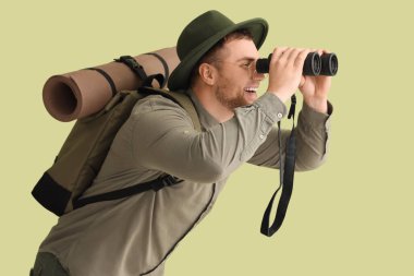 Dürbünden yeşil arka plana bakan genç erkek turist