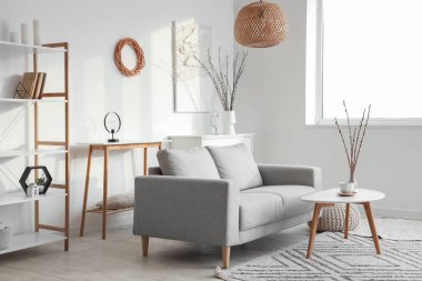 Kanepe, masa ve vazolarda söğüt dallarıyla aydınlık oturma odasının içinde.