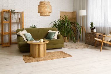 Beyaz oturma odasının içinde yeşil kanepe, lamba ve kahve masası var.