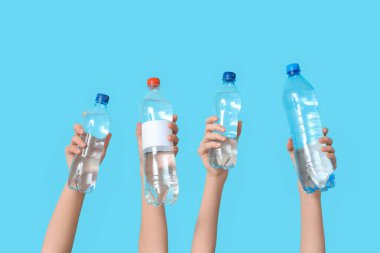 Renkli arka planda su şişeleri olan kadın eller, yakın plan.