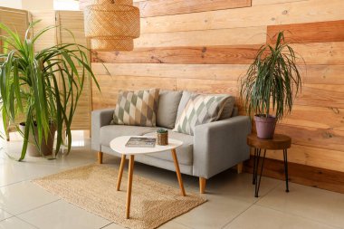 Oturma odasında kanepe, çiçekler, lamba ve kahve masası var.