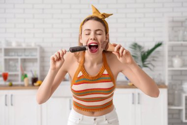 Evde farklı dondurmaları ısıran genç bir kadın.