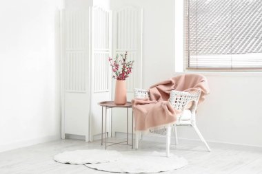 Işık odasındaki koltuğun yanındaki kahve masasında Sakura çiçekli vazo.