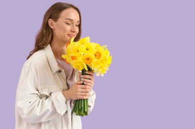 Leylak arka planında nergisleri olan güzel genç bir kadın.