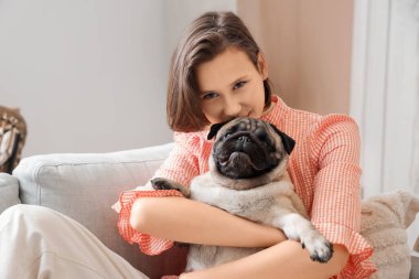 Evdeki kanepede oturan sevimli köpekli genç kadın.