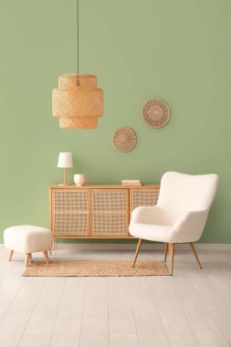 Yeşil duvarın yanında içi puf ve göğüs dolu beyaz koltuk.