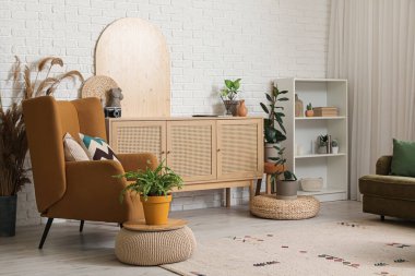 Oturma odasının içinde raf ünitesi, çekmeceler ve koltuk var.