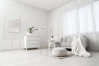 Perdesi, kanepesi ve masası olan aydınlık oturma odasının içinde.