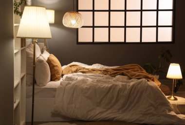 Geceleri rahat yatağı ve parlak lambaları olan modern yatak odasının içinde.