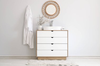 Çiçek açan dalları olan vazolar ve banyonun iç tarafındaki beyaz duvarın yanındaki çekmecelere batıyor.