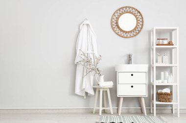 Çiçek açan dalları ve havlusu olan sürahi banyonun içindeki masada.