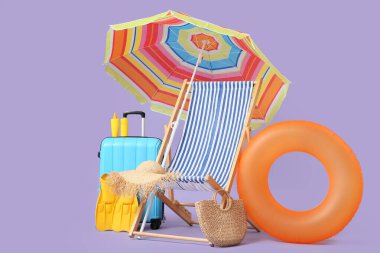 Çizgili iskemle, şişirilebilir yüzük, şemsiye, çanta ve eflatun arka planda plaj aksesuarları.