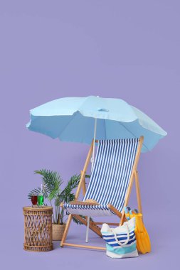 Çizgili güverte sandalyesi, ev bitkisi, plaj aksesuarları, kokteylli bardaklar ve leylak arka planda şemsiye.