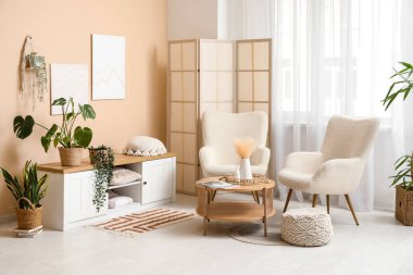 Katlanan ekranlı modern odanın içi ve bej duvarın yanındaki bitkiler.