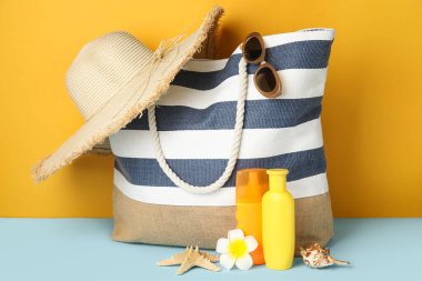Çizgili çanta, güneş kremi şişeleri ve plaj aksesuarları.