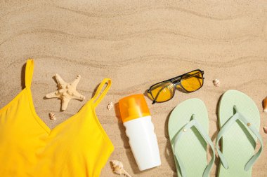 Arka planda kumda mayo ve plaj aksesuarları olan yaz kompozisyonu, yakın plan.