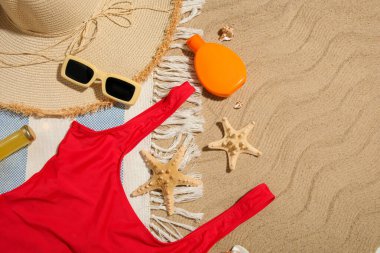 Arka planda güneş kremi, mayo ve kumsal aksesuarları olan kompozisyon