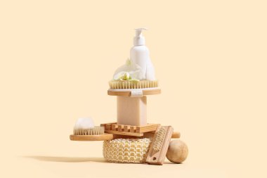 Duş jeli şişesi, masaj vücut fırçası ve bej arka planda sabun ile kompozisyon