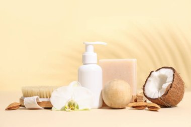 Duş jeli, masaj vücut fırçası, masaj topları ve bej arka planda hindistan cevizi içeren kompozisyon, yakın plan.