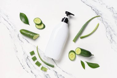 Duş jeli, salatalık ve mermer zemin üzerinde aloe vera yaprakları olan kompozisyon