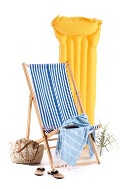 Çizgili iskemle, şişme yatak ve beyaz arka planda izole plaj aksesuarları.