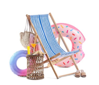 Çizgili iskemle, beyaz arka planda izole edilmiş kokteyl ve plaj aksesuarlarıyla dolu bir masa.