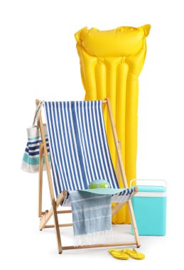 Buzdolabı, çizgili iskemle, şişme yatak ve beyaz arka planda izole plaj aksesuarları.